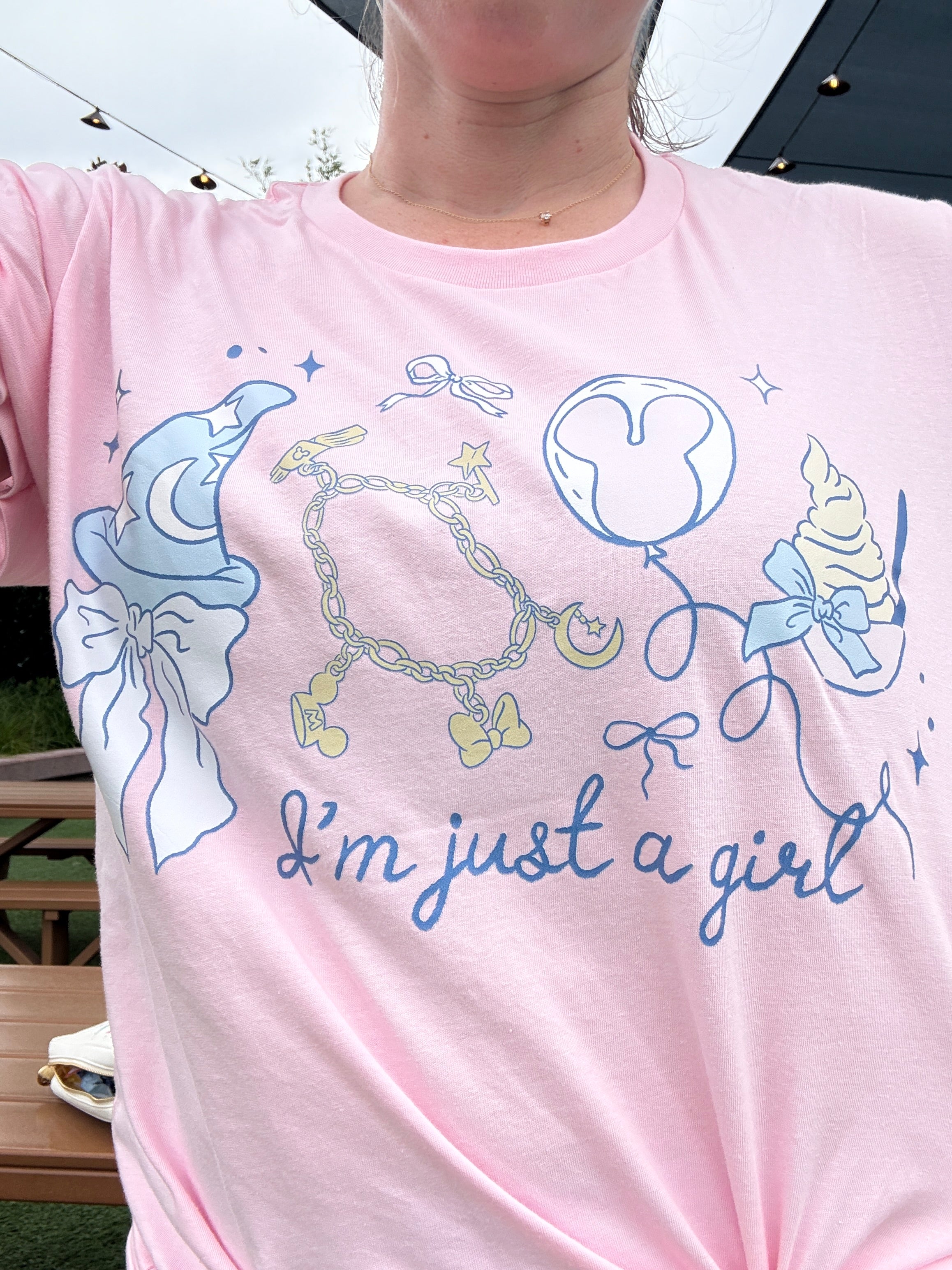Pink shirt with blue graphics and text on a person wearing it outdoors.